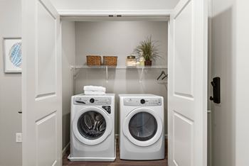 A white laundry room with two washing machines and a shelf above them.